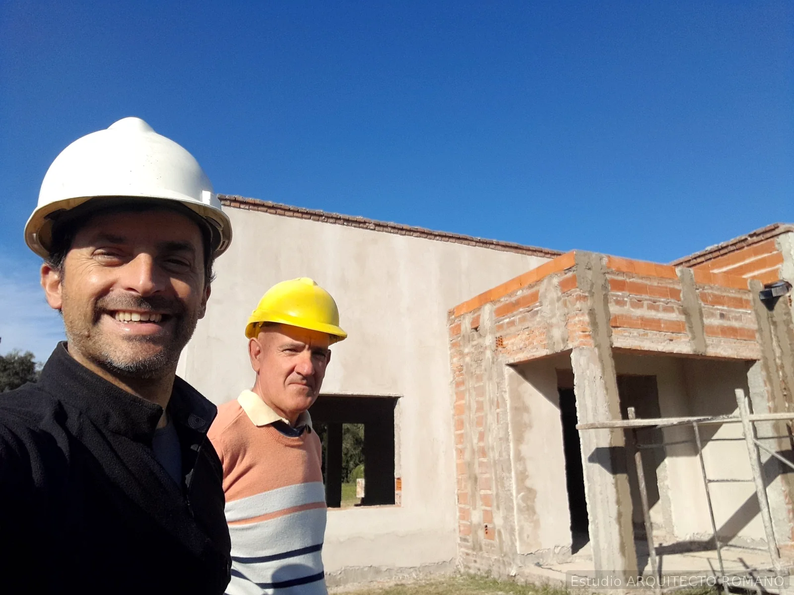 Arquitecto con casco blanco y constructor con casco amarillo durante seguimiento de obra